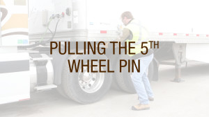 A truck driver pulling the fifth wheel pin